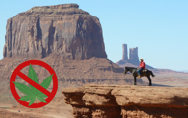 A no marijuana logo superimposed on an image of a sheriff on a horse next to a cliff